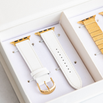 White watch strap with gold hardware on a white background