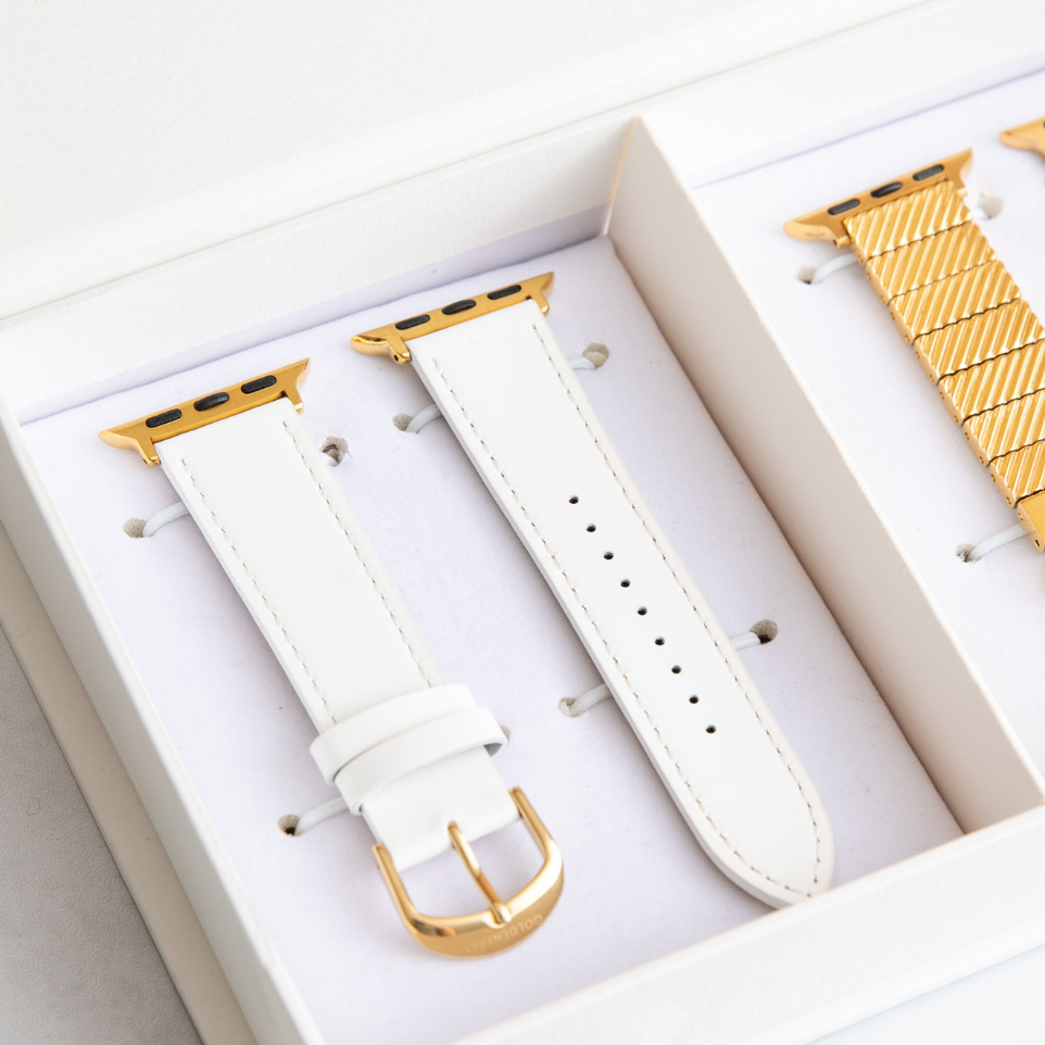 White watch strap with gold hardware on a white background